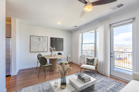 a living and dining area with a ceiling fan and glass doors with a view of the city